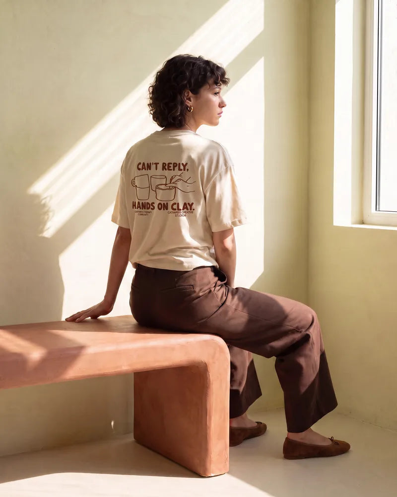 The woman sits on a terracotta plaster bench, back to the camera, looking at the window through stripes of sunlight. Image created or edited with AI.