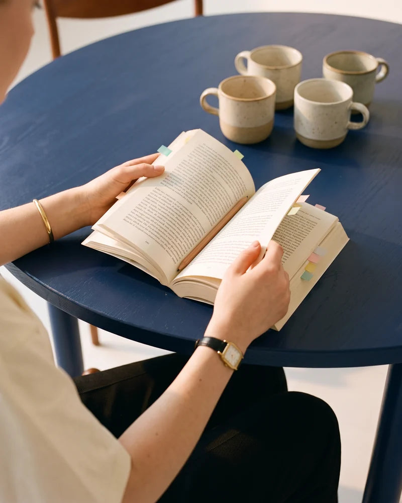 Detail: her hands holding the book open at the middle, with four mugs. AI-generated image.
