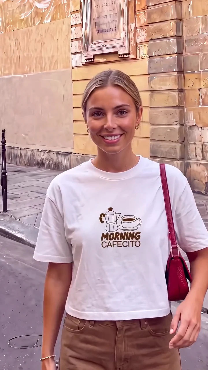 White Morning Cafecito Cropped T-shirt, brown trousers and a burgundy bag outdoors.