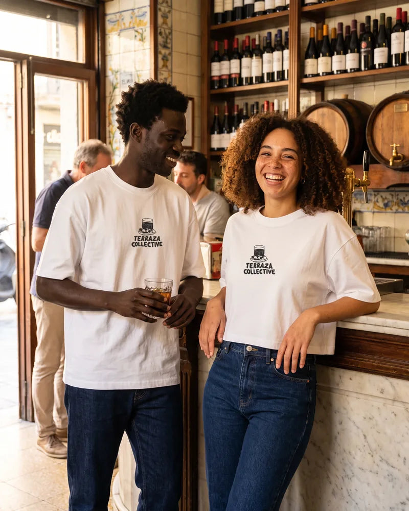 Two friends wearing the Terraza Collective relaxed and cropped T-shirts in a vermouth bar in Barcelona, front view. AI-generated image.